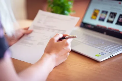 Iemand bekijkt een factuur naast een laptop